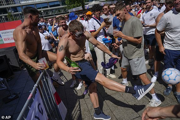 A man kicks a soccer ball as England's fans gather at Breitscheidplatz before the start of the final match between Spain and England at the Euro 2024 soccer tournament in Berlin, Germany, Sunday, July 14, 2024. (AP Photo/Ariel Schalit)