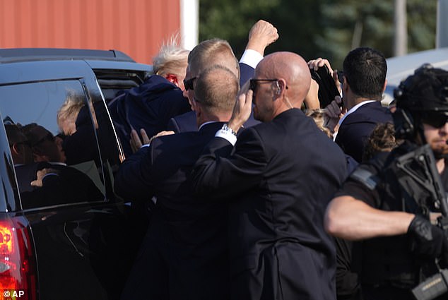 The president is seen being pushed into a Secret Service SUV, his raised fist still in the air