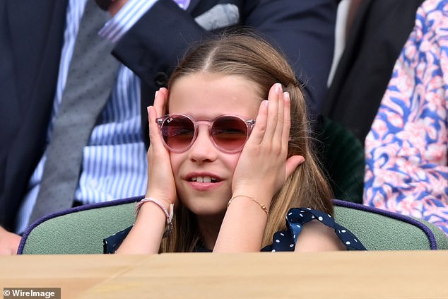 Charlotte wearing her pink Ray Ban sunglasses places her hands to the side of her head