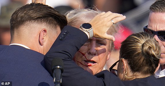 Republican presidential candidate former President Donald Trump is helped off the stage by U.S. Secret Service agents at a campaign event in Butler, Pa., on Saturday, July 13, 2024. (AP Photo/Gene J. Puskar)