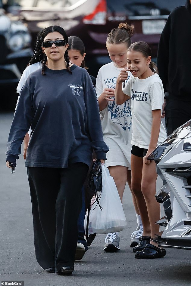 The 45-year-old mother-of-four borrowed her husband Travis Barker's navy-blue long-sleeve shirt from the Rollins Band's Australian 1992 tour and paired it with baggy black pants and matching ballet flats for their family meal out