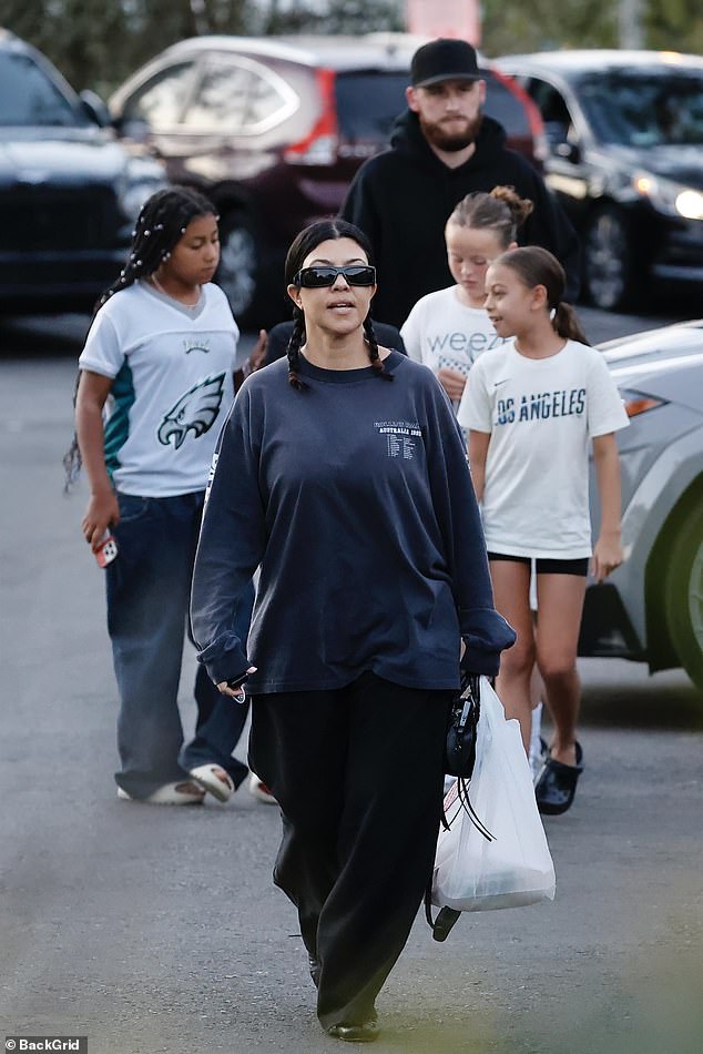 Kourtney - whose raven hair was styled in braids - and her mini-squad were joined by a black-clad bearded bodyguard, who towered over all five of them