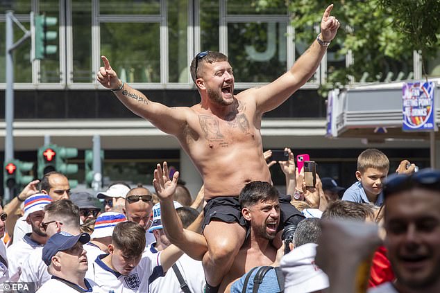 An England fan in Berlin chants while on top of his friend's shoulders