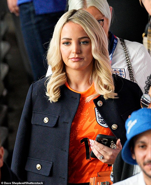 Pictured: Megan Davison - wife of Jordan Pickford - seen arriving in an orange England shirt and navy jacket