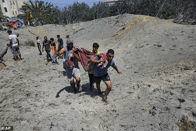 Palestinians evacuate a dead person from a site hit by an Israeli bombardment on Khan Younis, southern Gaza Strip, Saturday, July 13, 2024