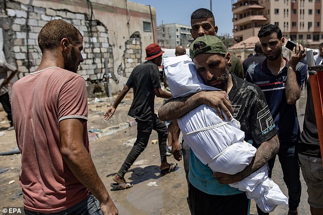 A Palestinian man carries the body of his son who was killed after an Israeli raid on the tents of displaced people in the Al-Mawasi area of Khan Yunis in the southern Gaza Strip, 13 July 2024