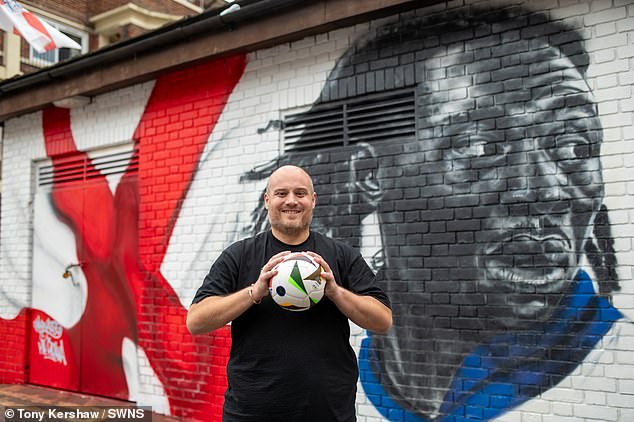 Local resident Chris Dowse 45 with the new mural to Eberechi Ezi on the Kirby Estate