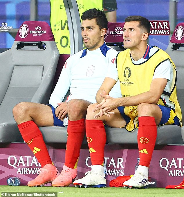 Rodri (left) takes his place on the Spain bench after being replace at half-time