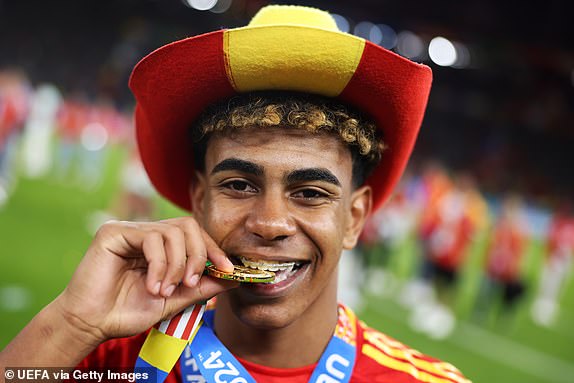 BERLIN, GERMANY - JULY 14: Lamine Yamal of Spain bites his winners medal after victory over England in the UEFA EURO 2024 final match between Spain and England at Olympiastadion on July 14, 2024 in Berlin, Germany. (Photo by Alex Pantling - UEFA/UEFA via Getty Images)