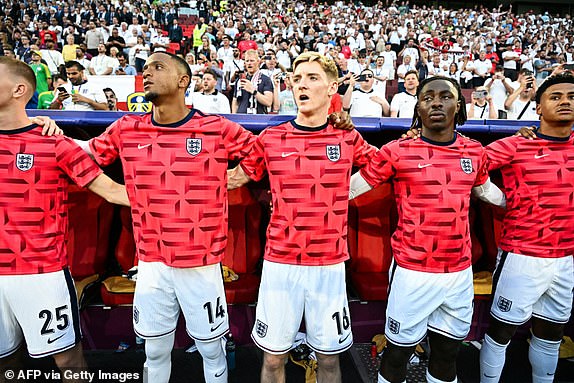 England's bench players England's defender #14 Ezri Konsa (2L), England's forward #18 Anthony Gordon (C) and England's forward #21 Eberechi Eze (2R) stand for the national anthem ahead of the UEFA Euro 2024 Group C football match between England and Slovenia at the Cologne Stadium in Cologne on June 25, 2024. (Photo by JAVIER SORIANO / AFP) (Photo by JAVIER SORIANO/AFP via Getty Images)