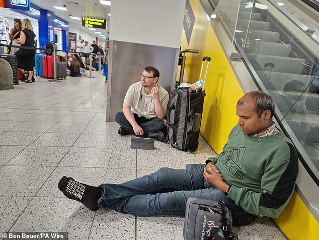 These two men at Gatwick took refuged by the escalators as they sought to wait out the chaos