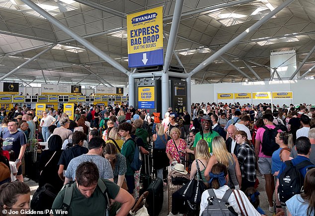 Passengers queue by the Ryanair check-in desk at London Stansted Airport in Essex