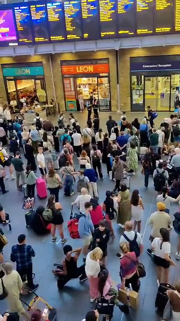 Large groups of commuters in Kings Cross wait for news when their trains will depart