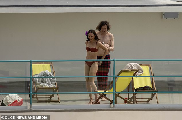 Other actors could be seen in swimwear on the upper levels, relaxing on yellow-coloured deckchairs