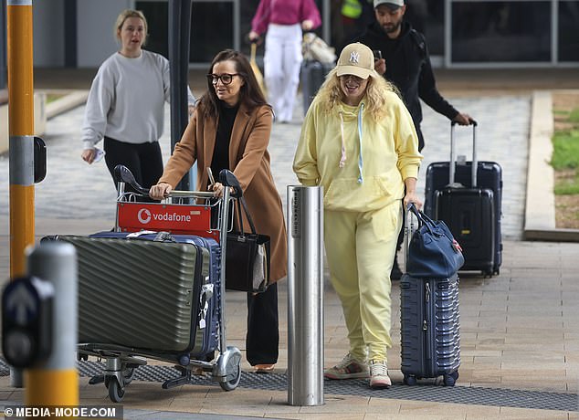 She pushed along a black suitcase with her designer bag resting on top and left the airport with a minder pushing along the rest of her luggage