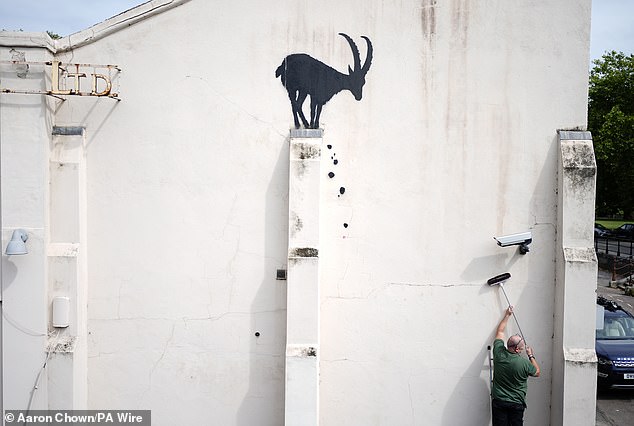 Employees move a CCTV camera back to its original position after Banksy moved it