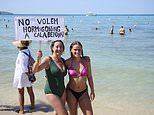 Anti-tourism protesters armed with banners and placards storm popular party beach in Majorca