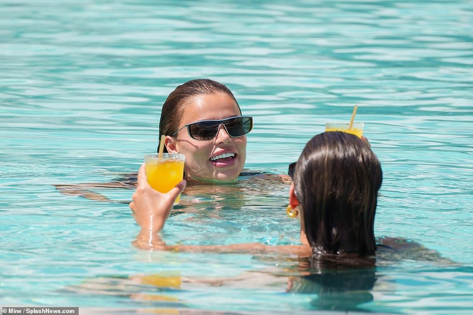 In this image, the sisters were holding on to orange beverages as they treaded water in the shallows