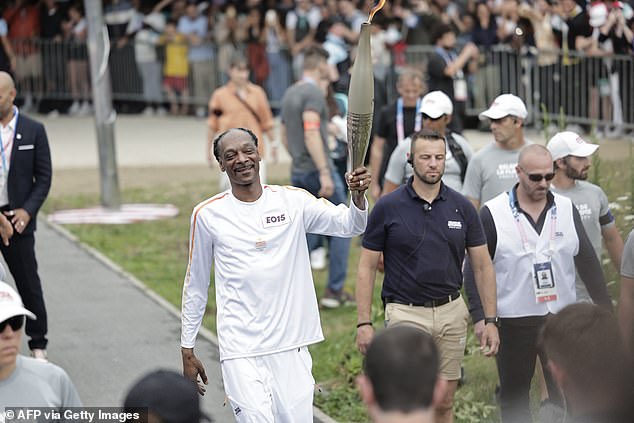 Snoop carrying the Olympic torch as part of the Paris 2024 relay on the day of the opening ceremony