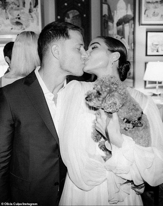 The husband and wife shared a kiss in a black and white shot with their adorable brown pooch in Olivia's arms