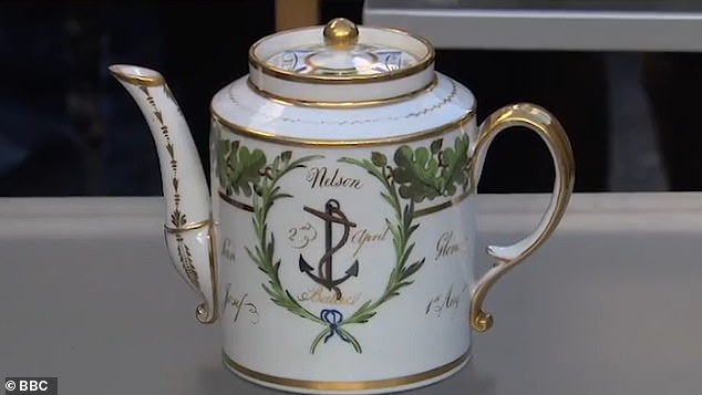 She presented a beautiful gold and white teapot with a design featuring leaves and an anchor, along with the word 'Nelson' printed on the front