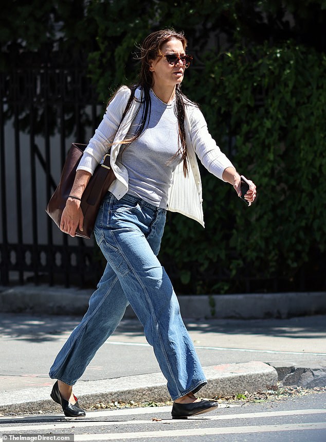 Katie Holmes stepped out for a stroll in Manhattan on Tuesday with wet hair while clad in a white cardigan over a grey t-shirt, blue Carpenter jeans, and black ballet flats