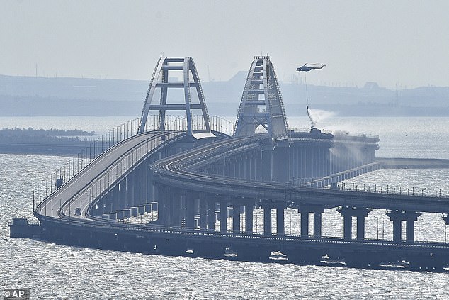 A helicopter drops water to stop fire on Crimean Bridge connecting Russian mainland and Crimean peninsula over the Kerch Strait, in Kerch, on Oct. 8, 2022