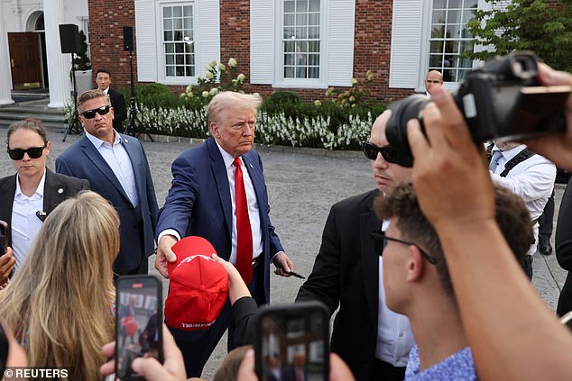 Trump signs hats and shakes hands after completing his unorthodox press conference