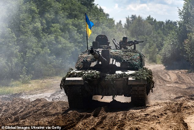 A Ukrainian soldier rides along a dirt road on a Challenger-2 tank on August 3, 2023 in Ukraine