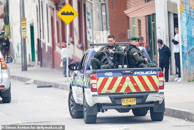 Armed officers sit in the back of a police vehicle ahead of Prince Harry and Meghan Markle's visit to a school in the Santa Fe district of Bogota