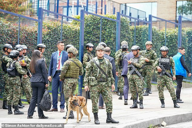 A soldier walking an armed forces dog stands alongside other servicemen outside La Giralda school before the visit