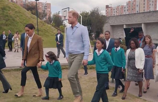 Prince Harry and Meghan hold the hands of two students as they are given a tour of Colegio La Giralda in Bogota yesterday