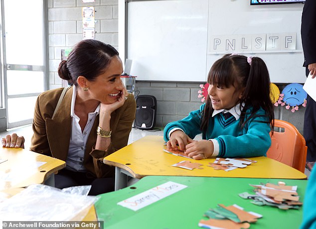 Meghan kneels down as she speaks to a young girl in the school's kindergarten this morning