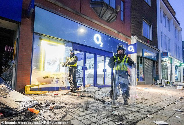 Riot police stand guard outside a damaged O2 shop in Hull, Yorkshire on August 3, 2024