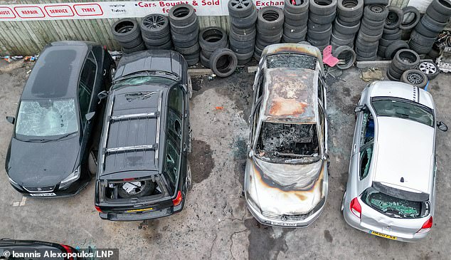 A burnt out and damaged cars are seen outside Humberside Carpets on August 4, following violent riots in Hull the day before