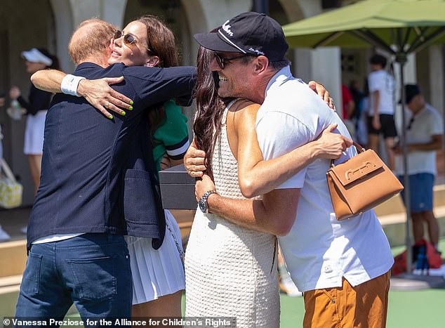 Harry hugs Kelly McKee Zajfen and Meghan hugs Julian at the tennis tournament on Saturday