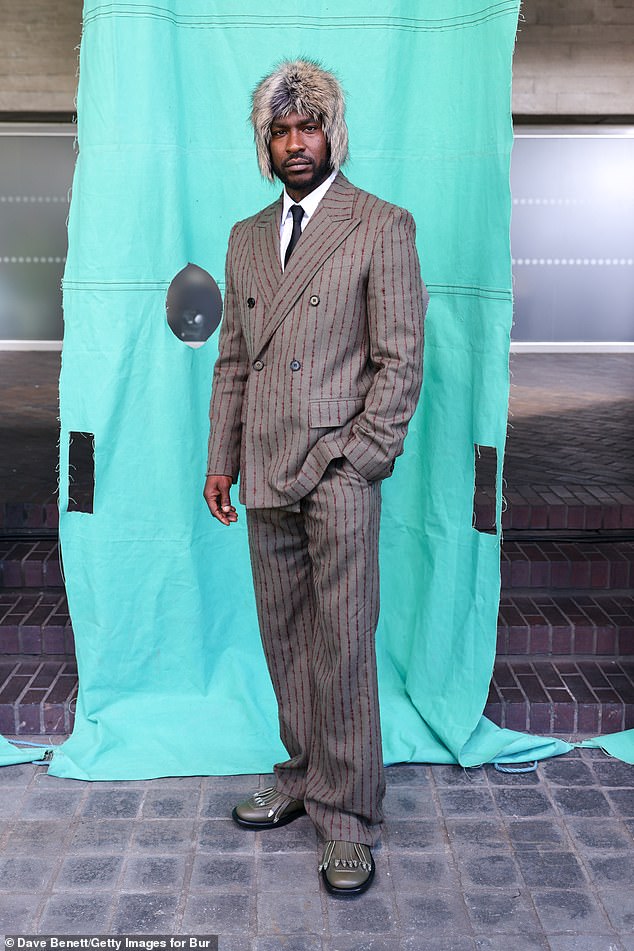 Skepta dressed to the nines for the event, sporting a grey and red pinstripe suit with a quirky faux-fur hat