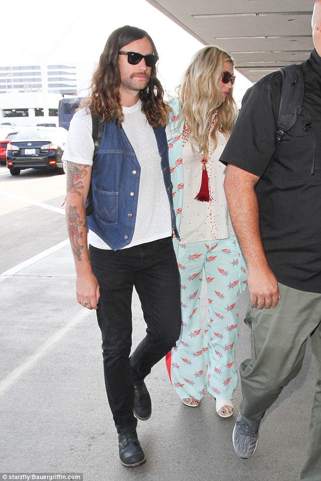 Edgy style: Kesha sauntered inside the terminal alongside Brad who rocked black jeans, white T-shirt and denim waistcoat