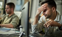 a man hold his head in front of a computer screen