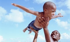 Father lifting son (6-8 years) in air at beach, son pretending to fly