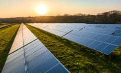 Rows of solar panels in a field at sunset