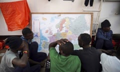 Rescued migrants look at a map of Europe onboard the Ocean Viking ship as it sails in the Mediterranean