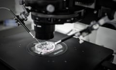 A petri dish under a microscope surrounded by medical tools