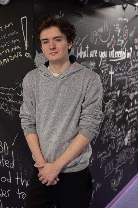 Alex Giles stands in front of a blackboard with inspirational messages and questions written on it.