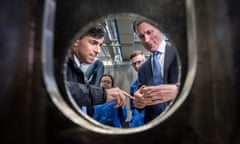 Rishi Sunak and Jeremy Hunt, the chancellor,  are seen through a round window examining a small component during a visit to BAE Systems’ submarines facility in Barrow-in-Furness last week.