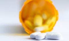 Opioid pain killers<br>close up of a group of white tablets with an out of focus prescription bottle in the background