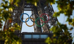 The Olympic rings are seen on a section of the Eiffel Tower with trees in the foreground