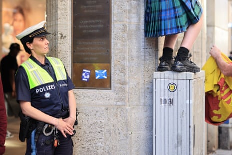 A German police officer sizes up a kilt-wearing Scotland fan.