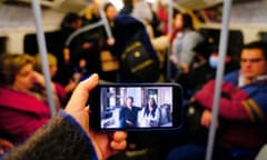 A phone screen held by a passenger on a London tube train showing the Duke and Duchess of Sussex's documentary