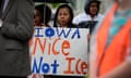 Woman in a raincoat holds an umbrella and a sign that says, "Iowa nice not Ice"